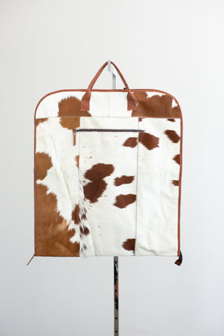 brown and white cowhide leather garment bag