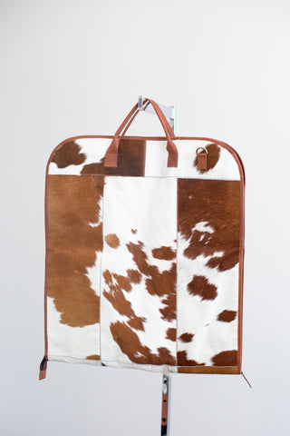 tan and white cowhide leather garment bag